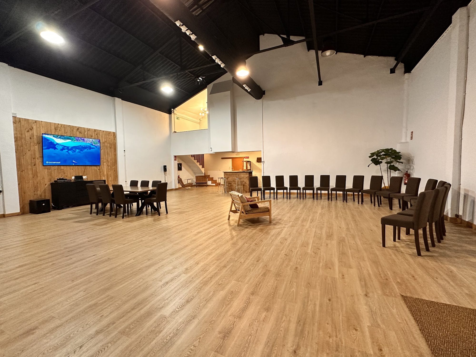 Sala principal vacía de M&F Espai+ con paredes blancas y suelo de madera